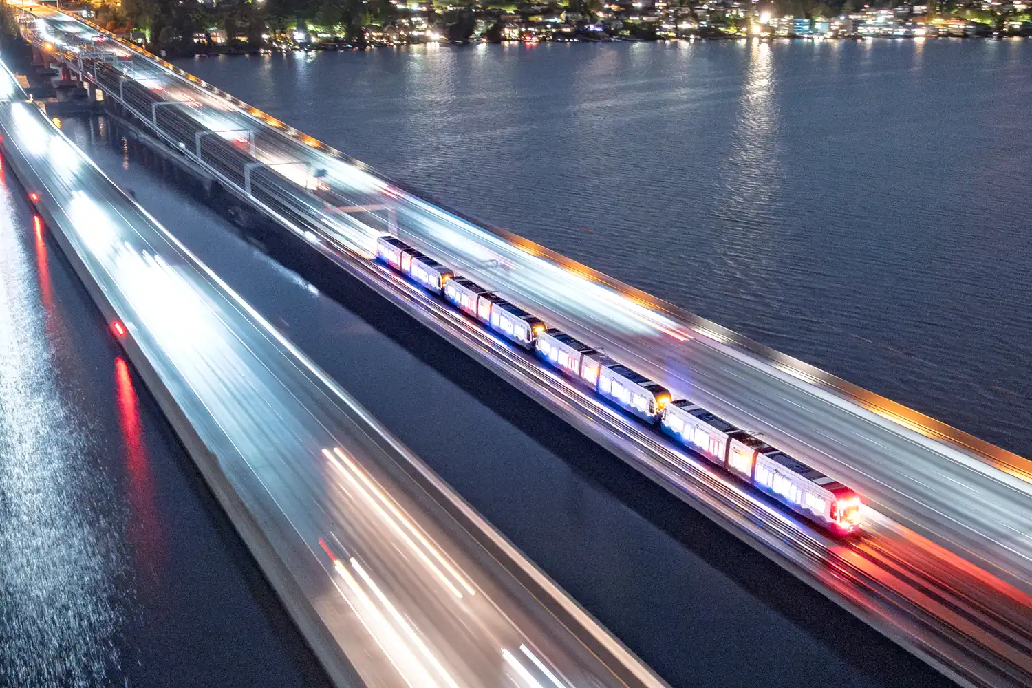 a Link light rail train traveling across the I-90 floating bridge at dusk