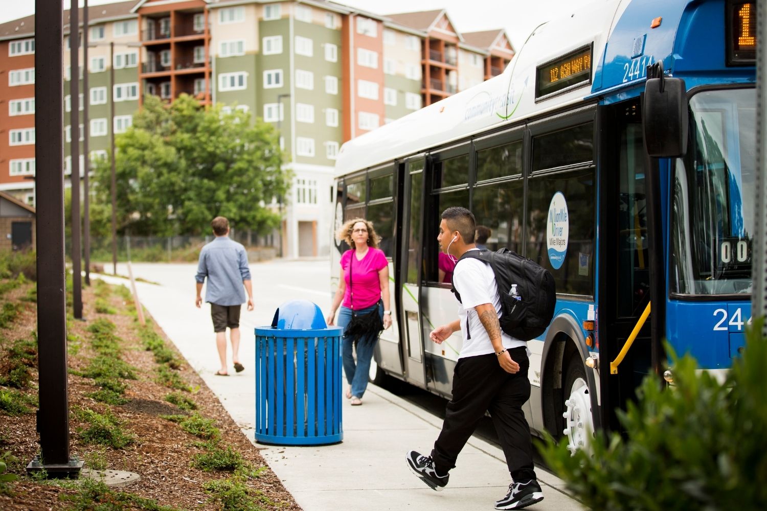 Three people getting off a bus at transit center.