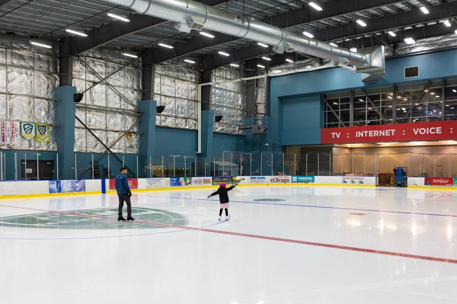 An adult and a kid ice skating.