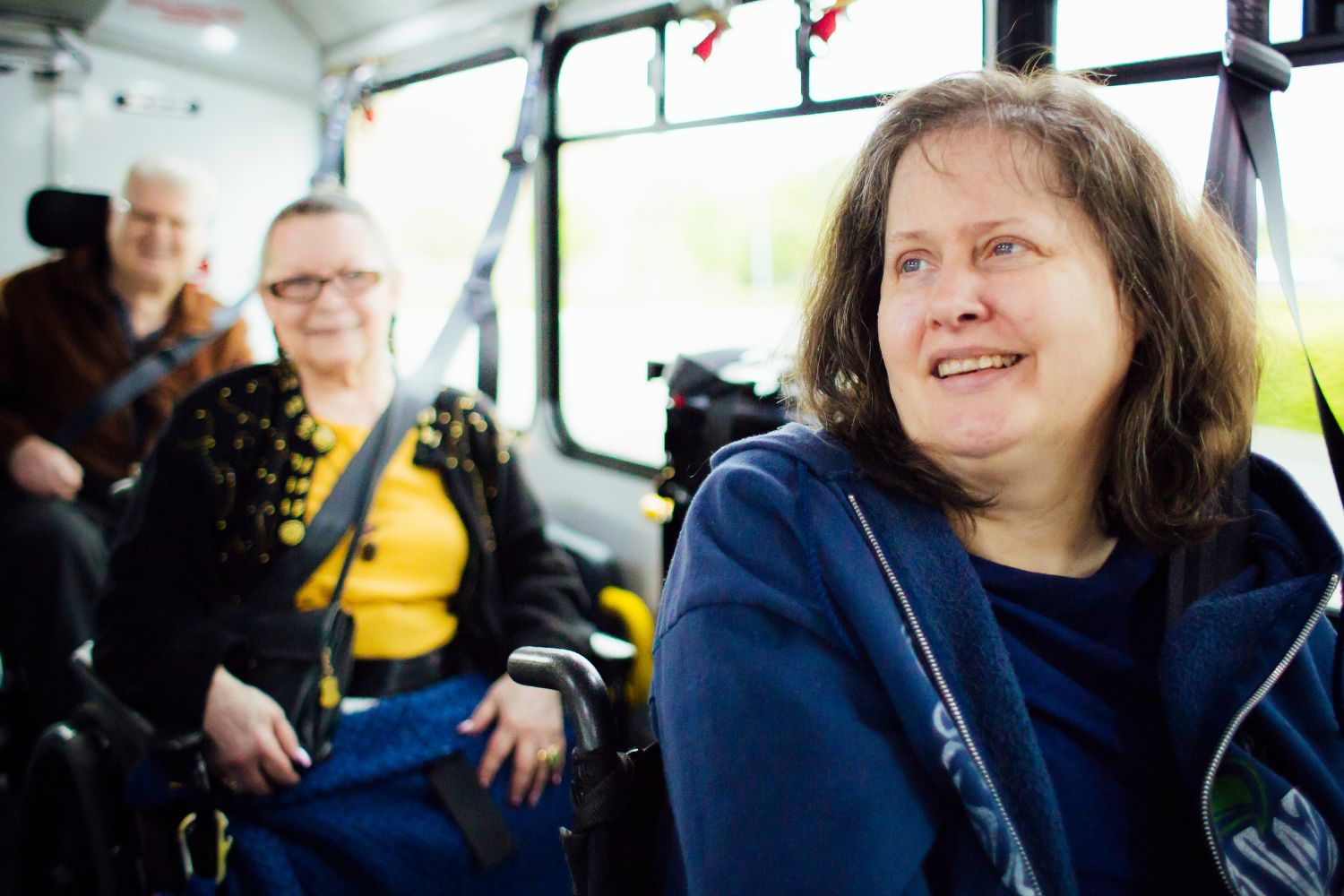 Three people sitting on a DART bus. They are all smiling. 