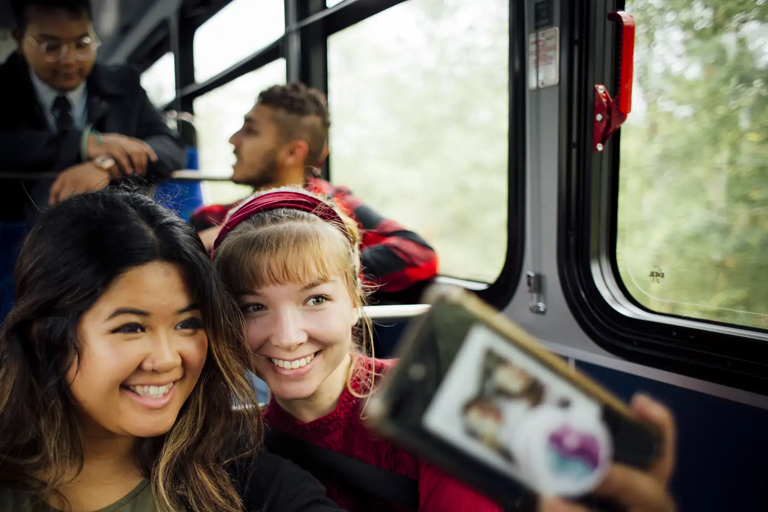 a group of riders on a bus chatting and taking a selfie