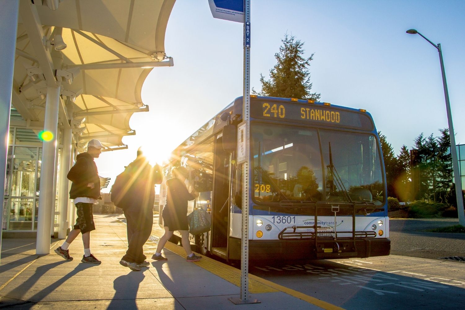 Three people boarding a bus at the Smokey Point Transit Center.