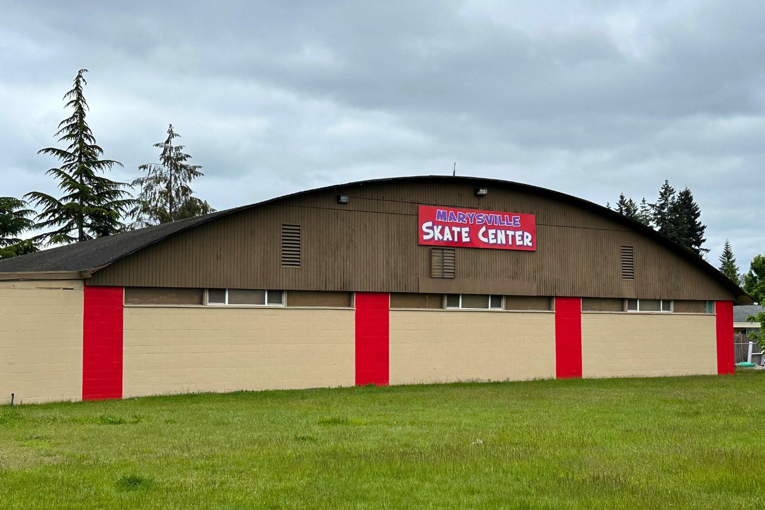 The outside of the Marysville Skate center. A brown building with red columns and a red sign. 