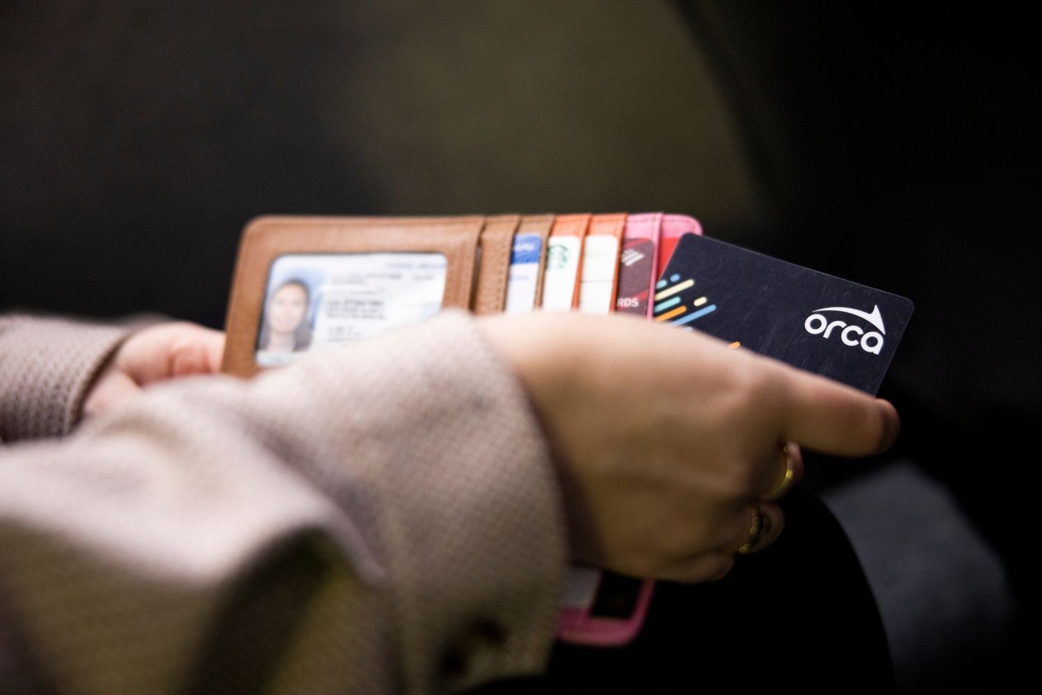 A hand taking an ORCA Card out of a wallet.