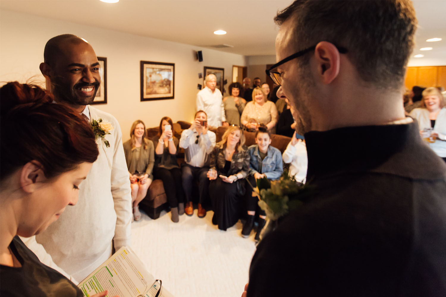 Jamie Johns officiates the marriage between Lance Lewis (left) and Phillip Jefferies (right) as friends and family watch in the background. 