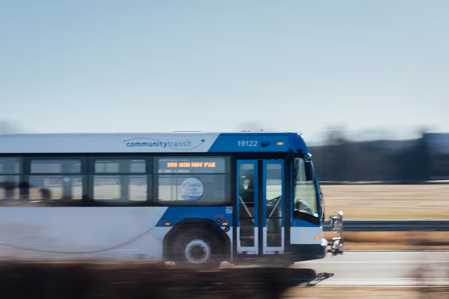 a Community Transit bus driving on a road past a field