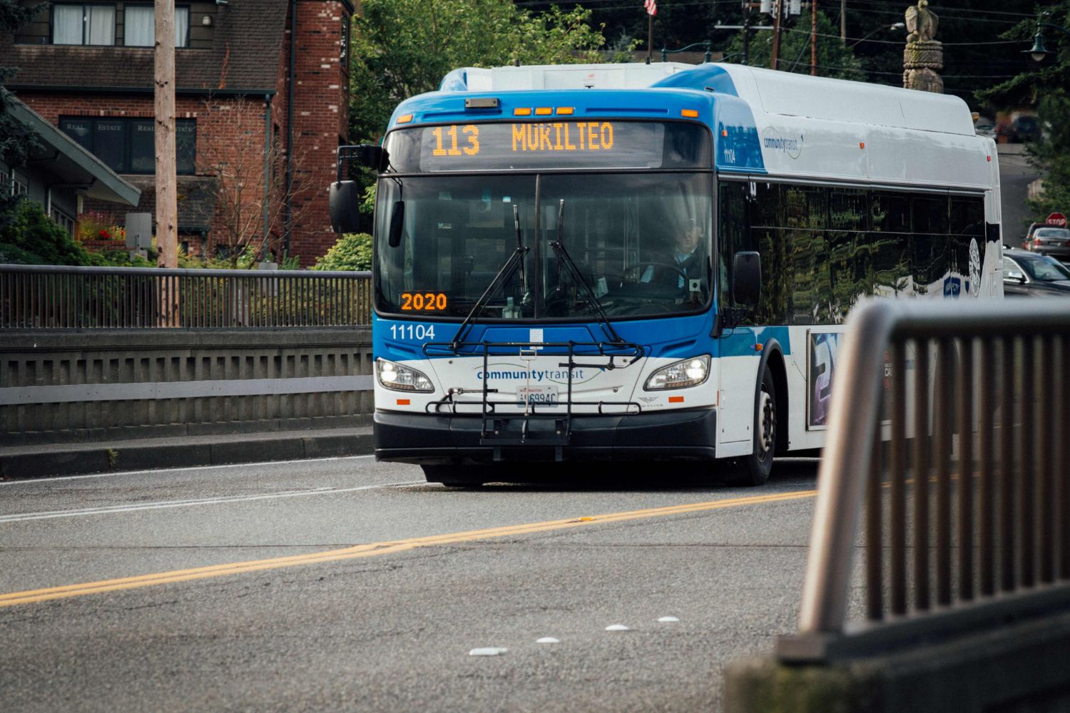 A picture of a blue and white Community Transit Route 113 bus driving up a hill.