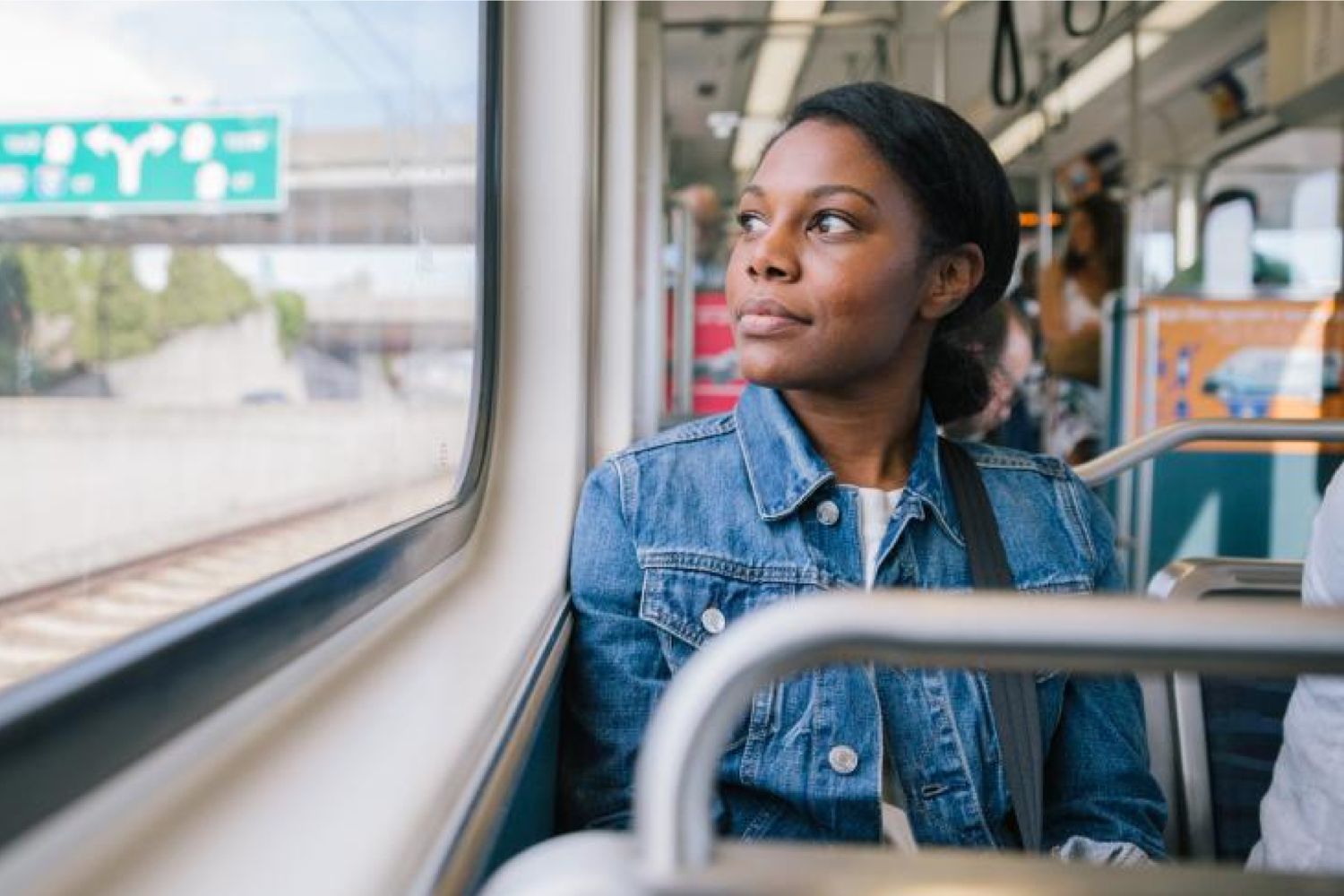 A woman sits on the light rail and looks out the window. 