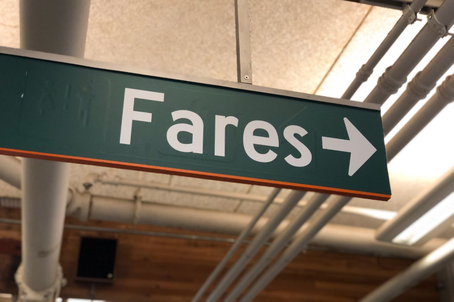 A dark green sign with white lettering says "Fares" with an arrow pointing right