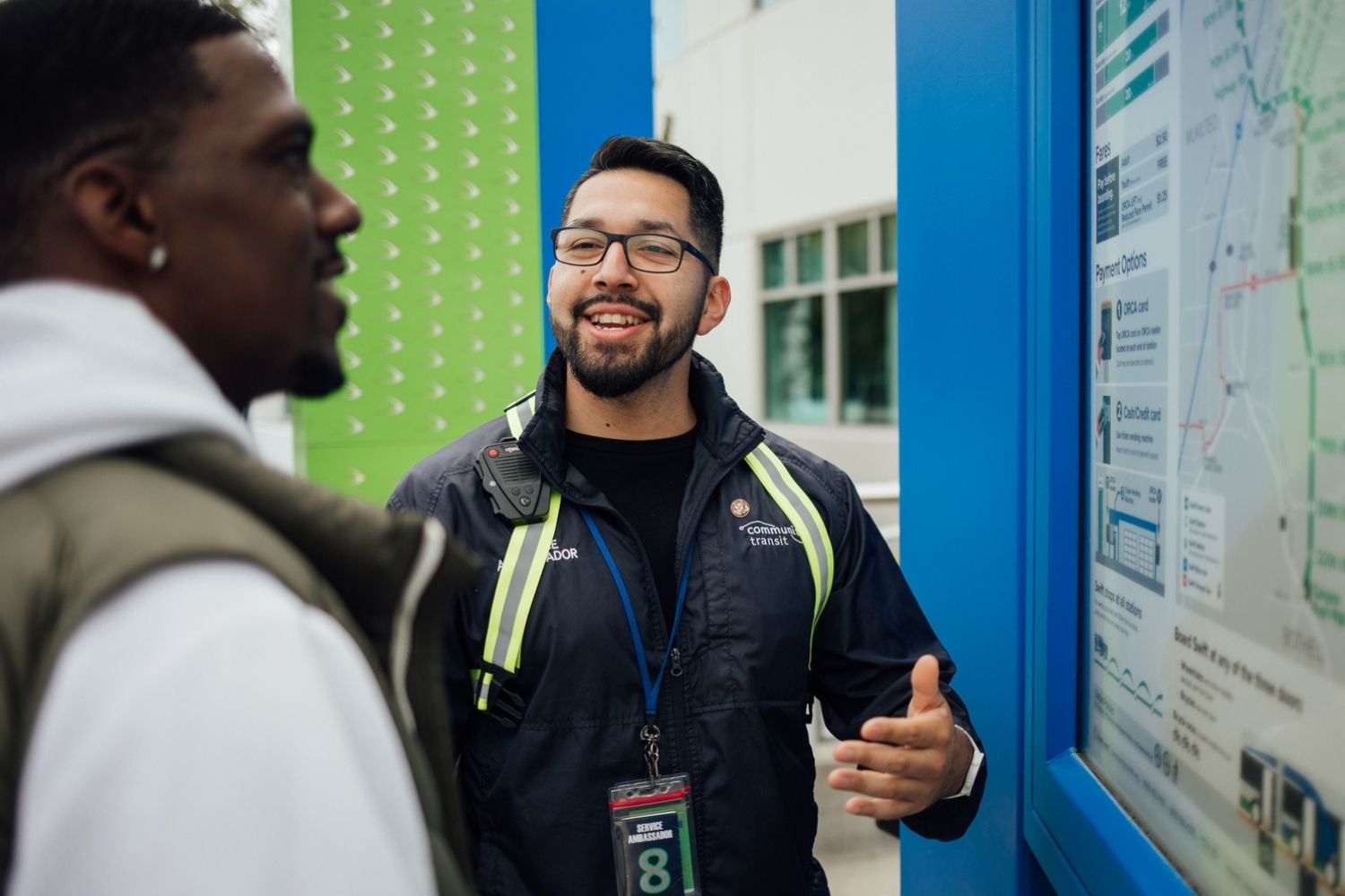 A Community Transit Service Ambassador speaks to a man about Swift bus service. They are looking at a Swift route map.