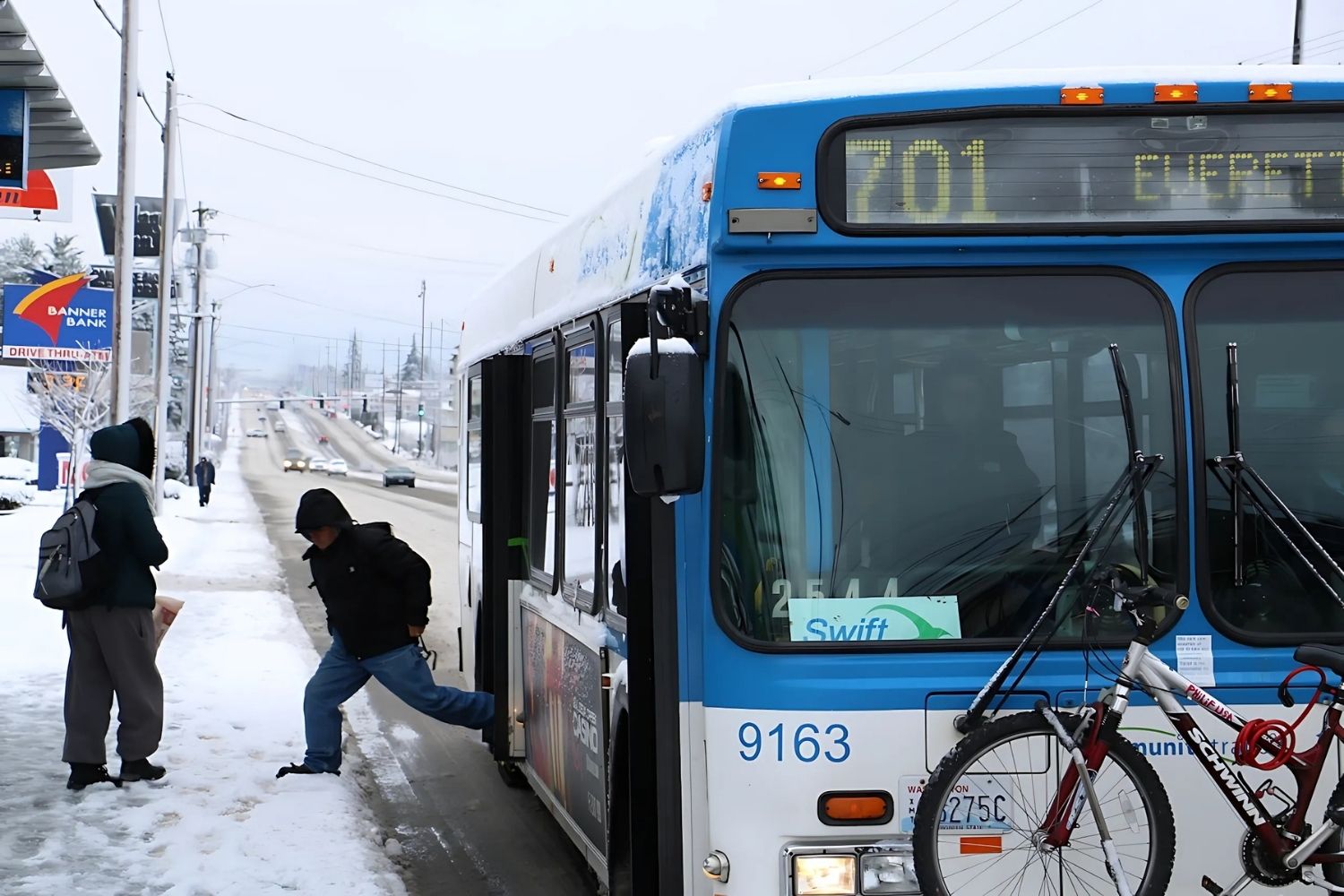 A rider deboards a 40-foot bus which is standing in for a regular Swift bus due to snowy road conditions