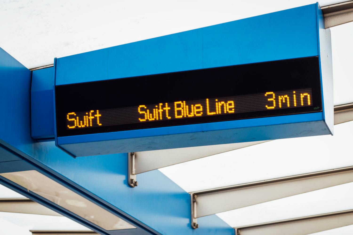 A digital sign at a Swift Blue Line station shows a bus will arrive in 3 minutes