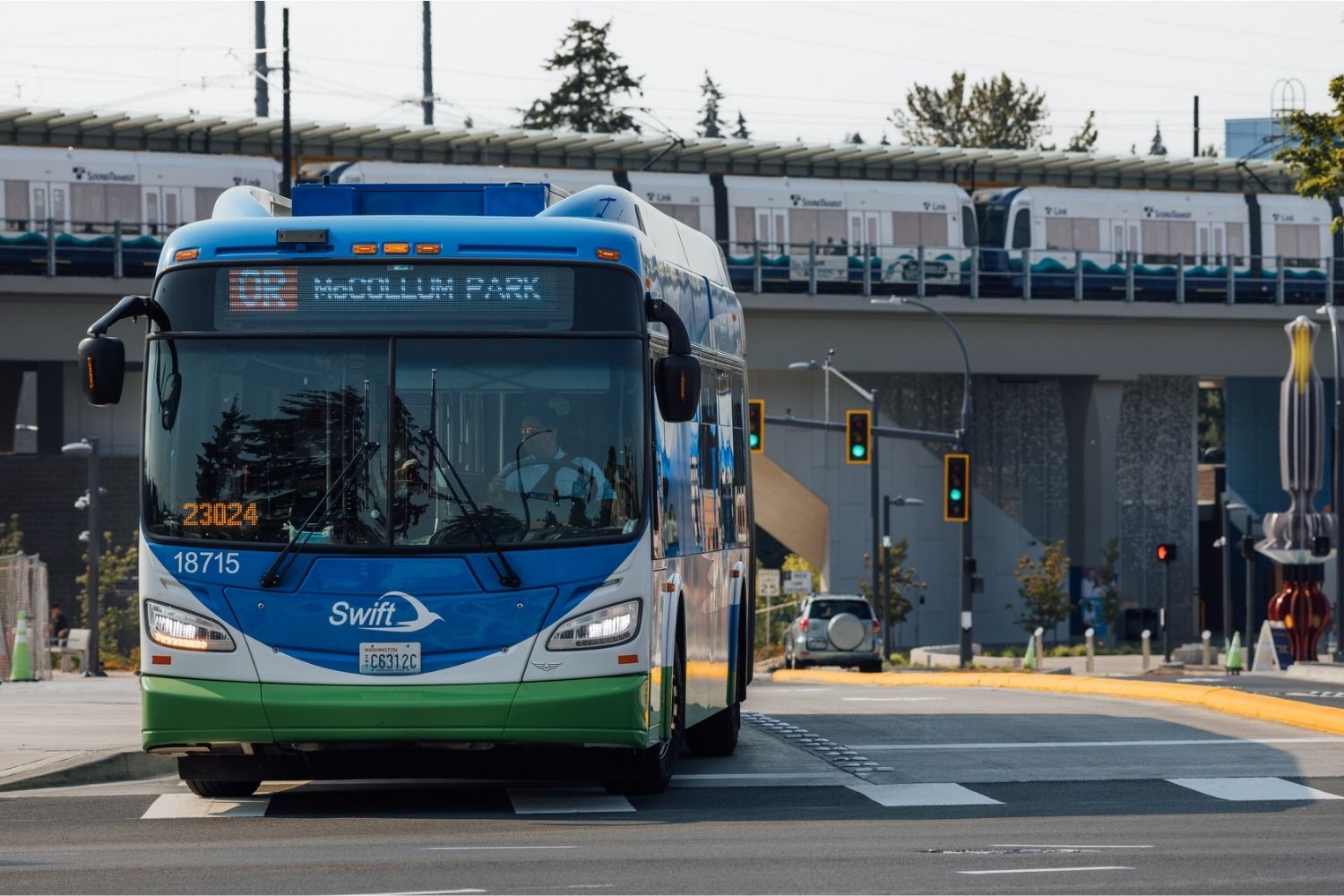 A Community Transit Swift Orange bus waits at a traffic light at Lynnwood City Center Station.