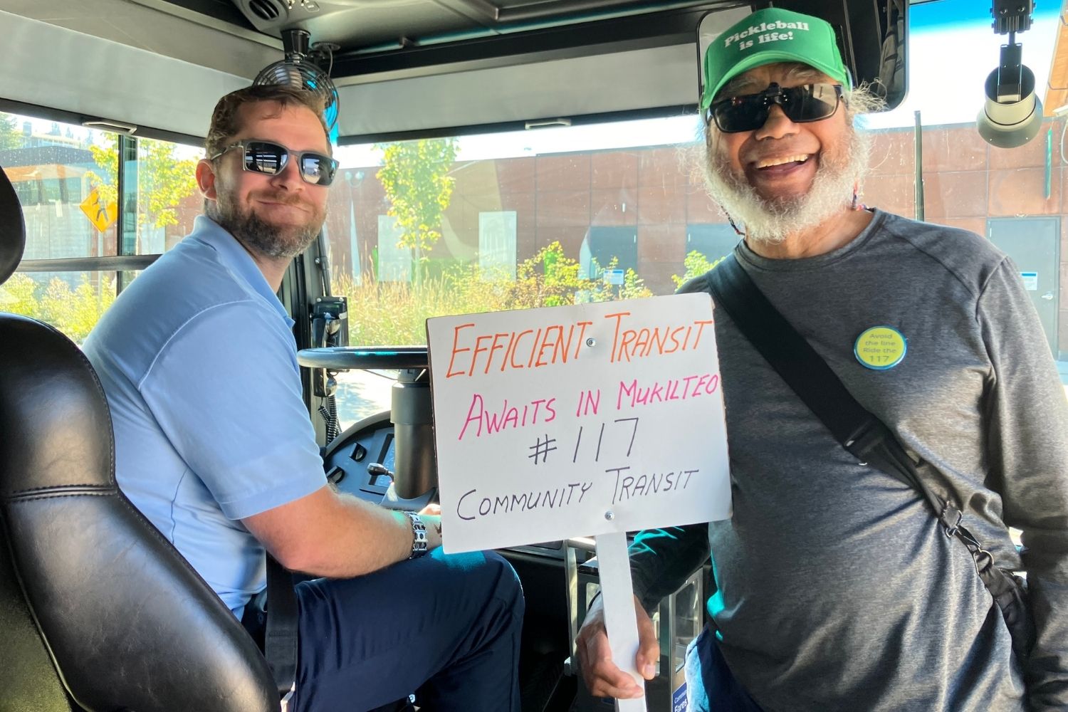 A Community Transit bus driver and a male passenger are all smiles on the Route 117 bus.