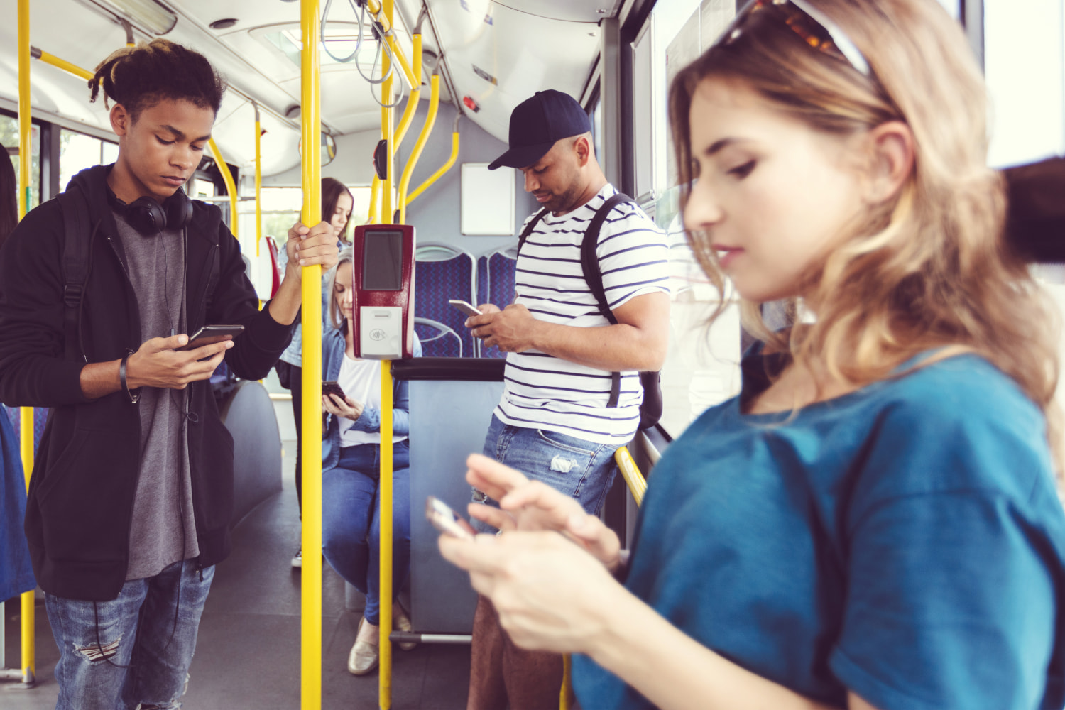 Young adults using their mobile devices on the bus