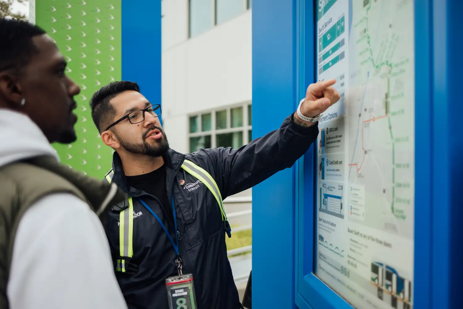 a Service Ambassador assisting a rider with a posted route map