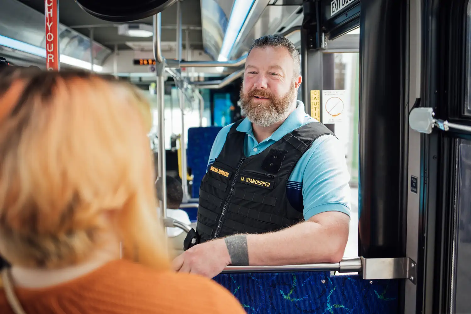 a Social Worker speaking to a rider on a bus