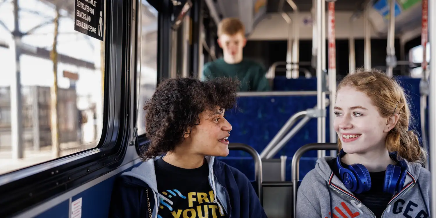 two youth riders chatting while riding the bus