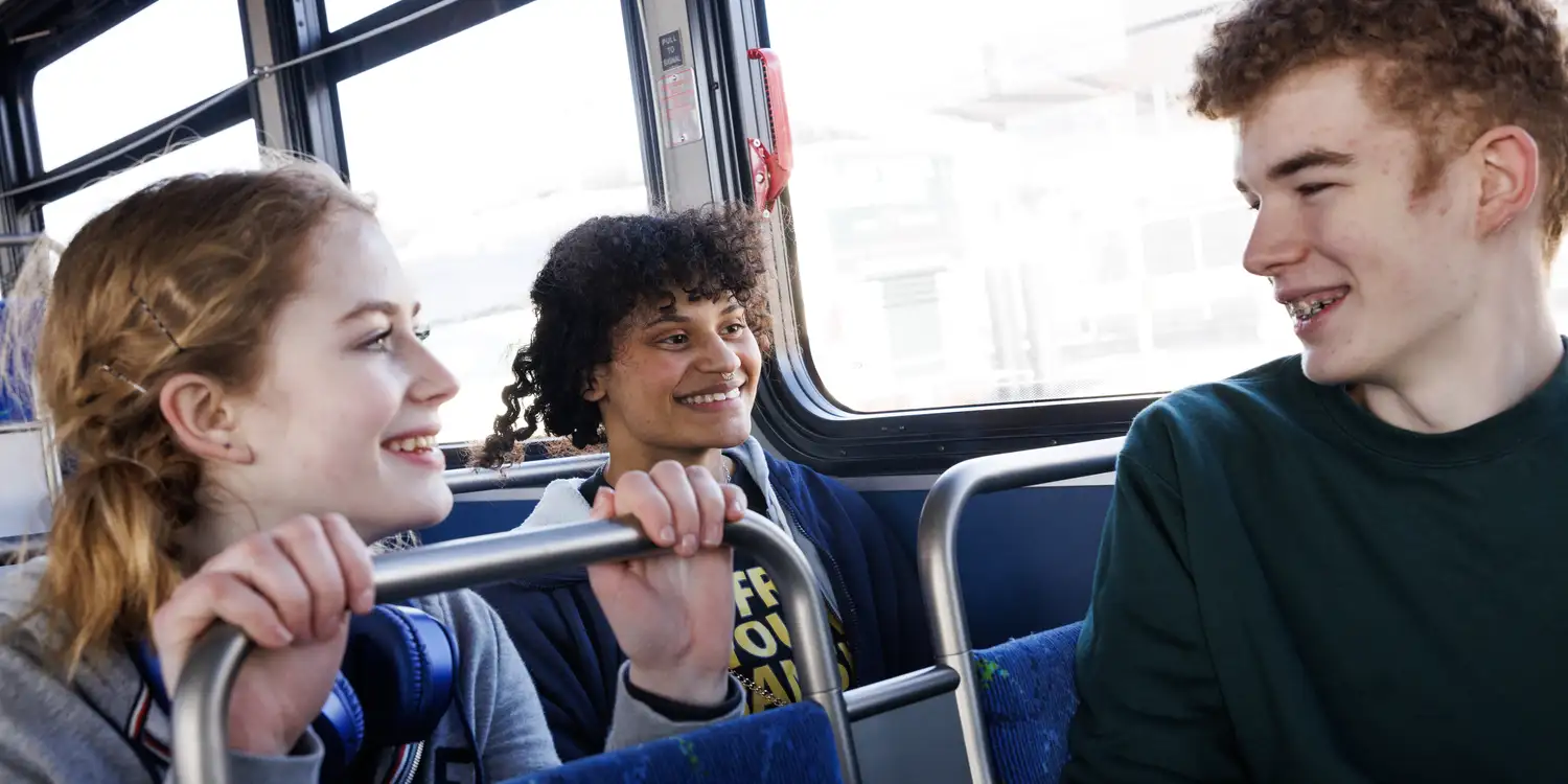 youth riders riding the bus together and smiling