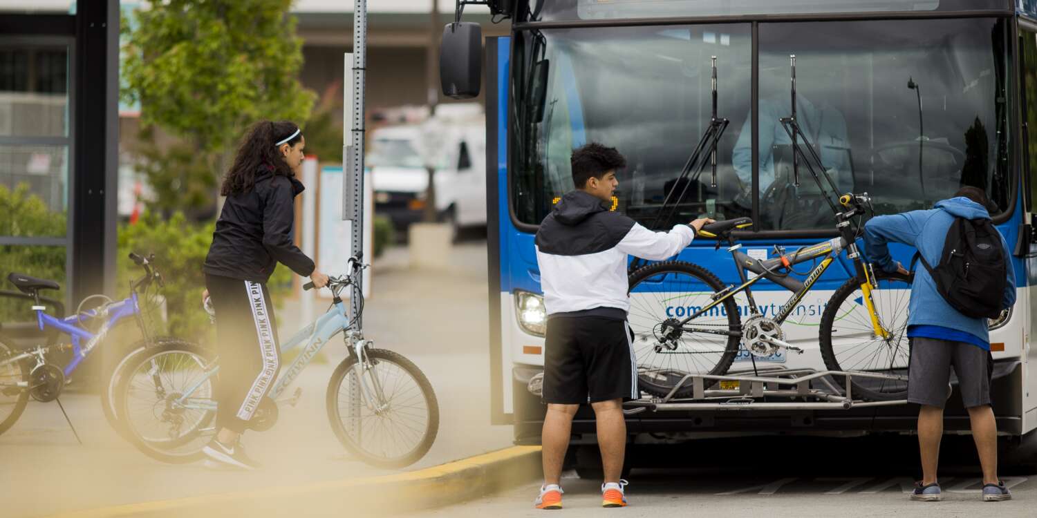 Riders load their bike on a bus bike rack