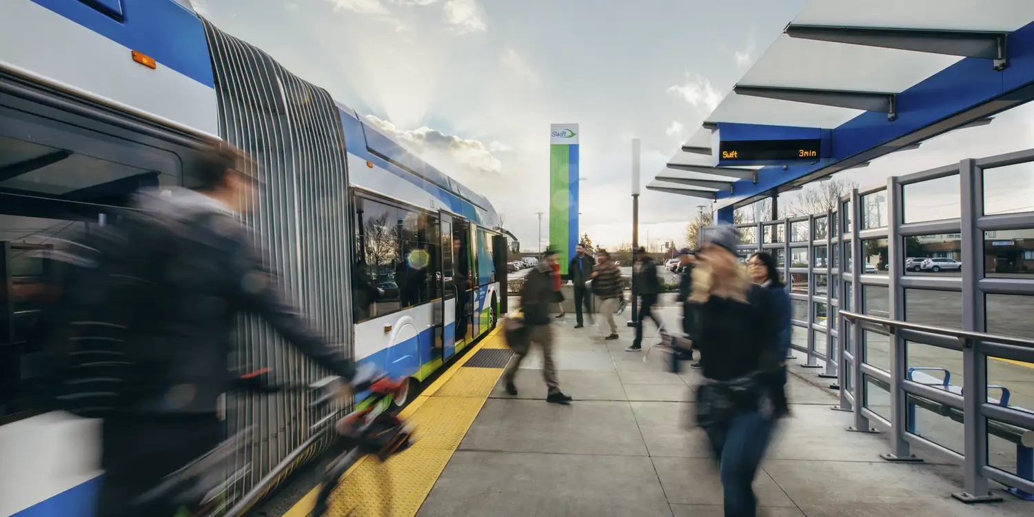 a Swift bus at a station with riders departing and boarding