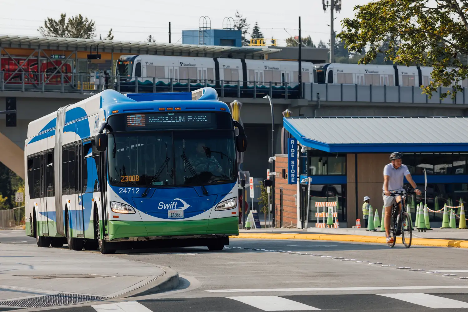 a Swift bus arriving at Lynnwood City Center Station with the CT Ride Store and Link light rail in the background